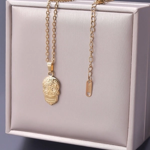 Macro shot of 18k gold plated stainless steel sugar skull pendant with floral patterns
