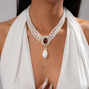 Gros plan d'un collier de perles à trois rangs avec gemme violette et pendentif goutte