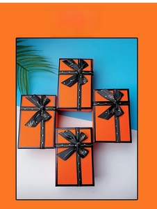 Set of four orange gift boxes with black happy ribbons and textured finish