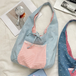 Detail of fabric tote bag with bow print, lace trim, and pink checkered inner lining
