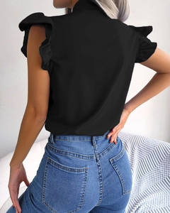 Detail view of black sleeveless ruffle top with side tie bow and casual denim jeans