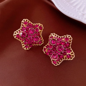 Dettaglio degli orecchini a forma di stella con strass fucsia su tessuto di velluto
