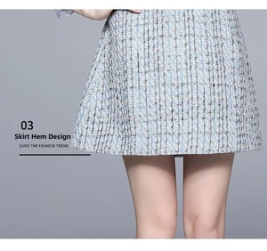 Detailed close-up of blue tweed A-line skirt hem showing intricate woven texture and pleated design