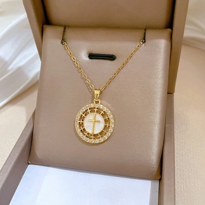 Macro shot of gold cross necklace with crystal pavé and mother of pearl inlay
