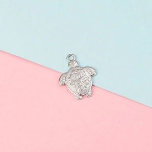 Detailed silver sea turtle pendant with embossed patterns on pink and blue background