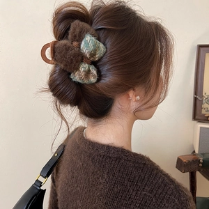 Brown faux fur bow hair claw clip with blue plaid pattern worn by a model in autumn