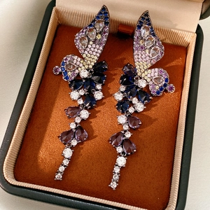 Détail de boucles d'oreilles papillon colorées avec cristaux dans un écrin de luxe