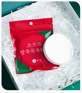 Detail of single disposable compressed bath towel in gift box with red and green packaging