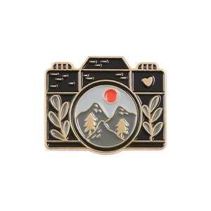 Retro black camera enamel pin with golden mountain landscape and heart details