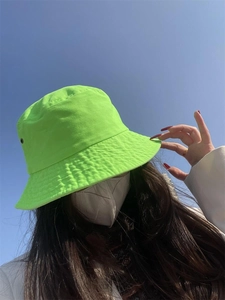 Neon green sun hat detail against blue sky background, showing fabric texture and style