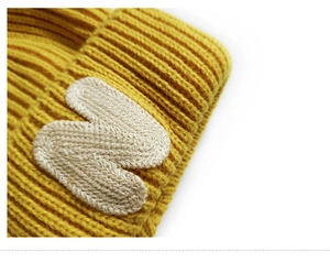 Macro view of yellow knitted texture and white embroidered letter N on baby beanie