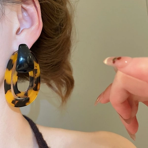 Close-up of model wearing oversized leopard print resin hoop earrings with glossy finish