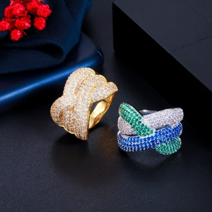Dettaglio di anelli a onde larghe con zirconi multicolore e finitura oro-argento