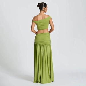 Detail view of the side pleats and slit on the high-waist green two-piece maxi skirt