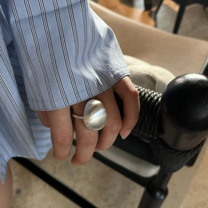 Detail of a oversized silver oval ring featuring a modern matte brushed metal finish