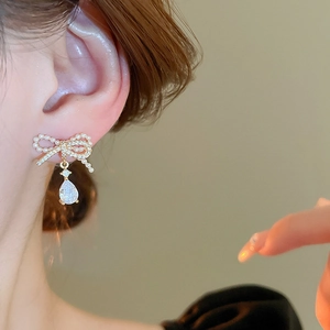 Elegant gold drop earrings with pearl bow and teardrop zircon crystal on model
