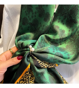 Détail d'un foulard en soie à motif léopard fleuri et une pince élégante en perles