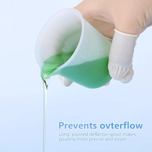 Detail of 100ml silicone measuring cup with a long pointed spout pouring green liquid