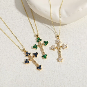 Detailed view of three gold cross necklaces with blue green and white crystals