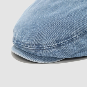 Dettaglio macro del berretto in denim blu scuro con trama saia e doppia cucitura