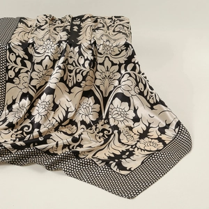 Close-up of silk satin scarf featuring beige damask floral patterns and polka dot borders