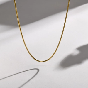 Detail of a polished golden square snake bone chain necklace with metallic luster