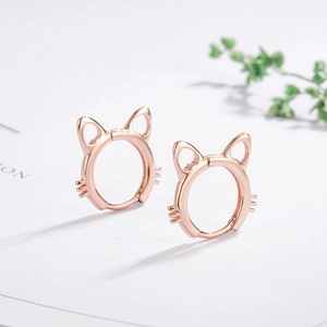 Detailed close-up of rose gold cat-ear shaped earrings on white card background