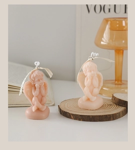 Close-up of two pink angel-shaped scented candles on a minimalist wooden tray base