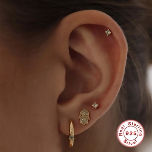 Close-up of S925 sterling silver Hamsa Hand and stud earring set worn on ear