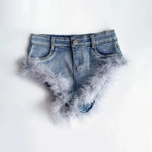 Detail der blauen Denim-Shorts mit flauschigem grauem Federbesatz und Metallknopf