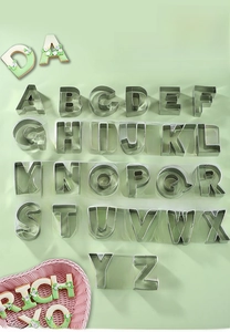 Macro view of 26-piece stainless steel alphabet cookie cutters on green background