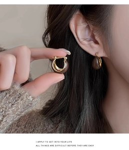 Detail of ethnic retro tiger eye style earrings with a polished brown resin and gold finish