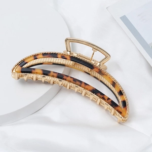 Close-up of golden metal arch hair claw with tortoiseshell acetate on white silk