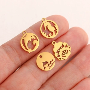 Macro detail of gold sea horse, dolphin, and shell charms held by hand for size