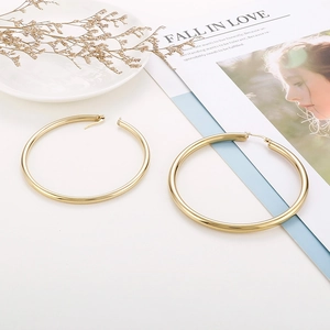 Macro shot of large 18K gold plated hoop earrings with high polish finish on elegant props