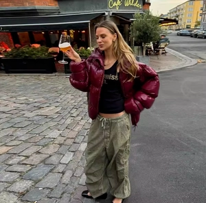 Street style view of a shiny burgundy puffer jacket paired with green cargo trousers