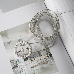 Close-up of a clear PVC belt featuring silver bead edges and a round pearl-adorned buckle