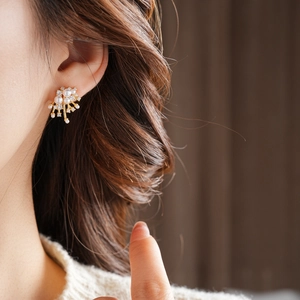 Close-up of elegant gold flower stud earrings with pearls and rhinestones on model