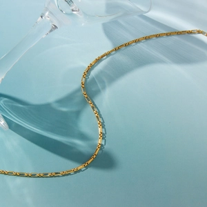 Vue détaillée d'un collier en acier titane doré avec des ombres de reflets d'eau