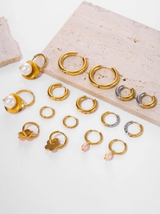 Detailed close-up of 18k gold plated stainless steel earrings set on a stone display