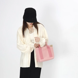 Pink canvas handbag paired with pleated shirt and black bucket hat for casual daily use