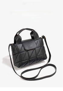 Detailed top view of black quilted fashion handbag with handle and long shoulder strap