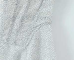 Detail of white corset dress featuring black polka dots and structural boning texture