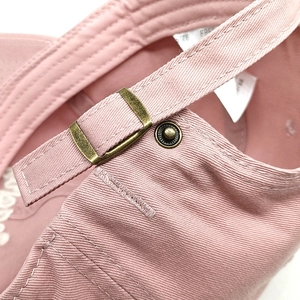 Detail of vintage copper buckle and cotton twill fabric on pink baseball cap