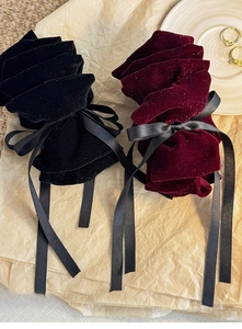 Close-up of elegant velvet jewelry pouches in black and burgundy with satin bow detailing