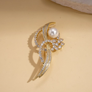 Detailed close-up of 14k gold plated brooch with zircons and pearl on warm stone base