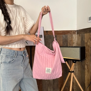 Detail of pink quilted pleated shoulder bag featuring a white woven brand label and strap