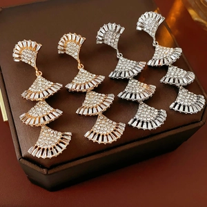Close-up of gold and silver layered fan-shaped tassel earrings with sparkling rhinestones