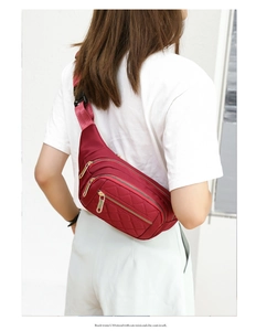 Close-up of wine red waist bag featuring quilted diamond pattern and gold metal zippers