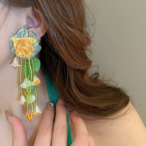 Gros plan de boucles d'oreilles muguet fait main avec glands fleuris sur un modèle